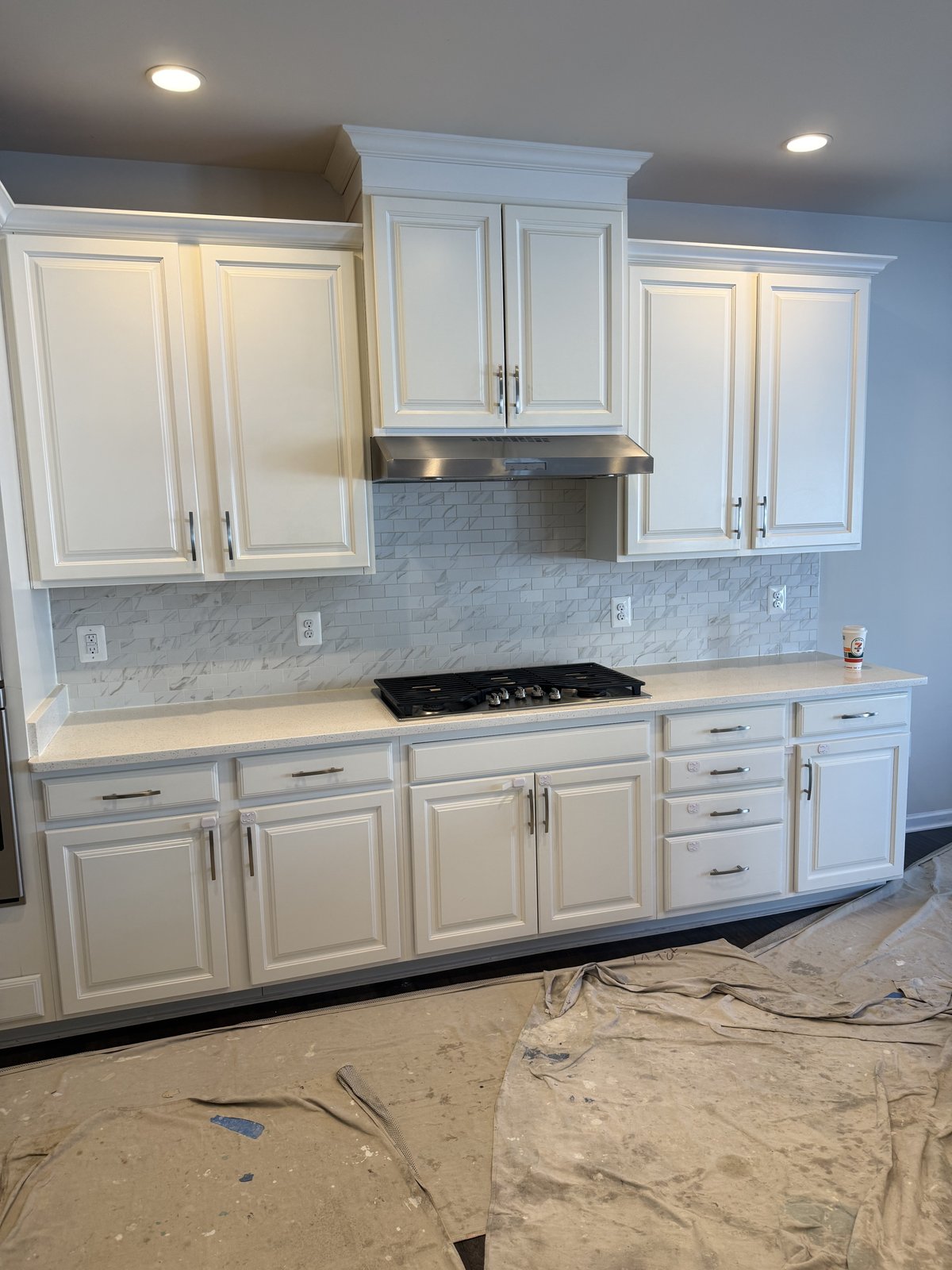 White kitchen cabinetry wall with gas cooktop and range hood