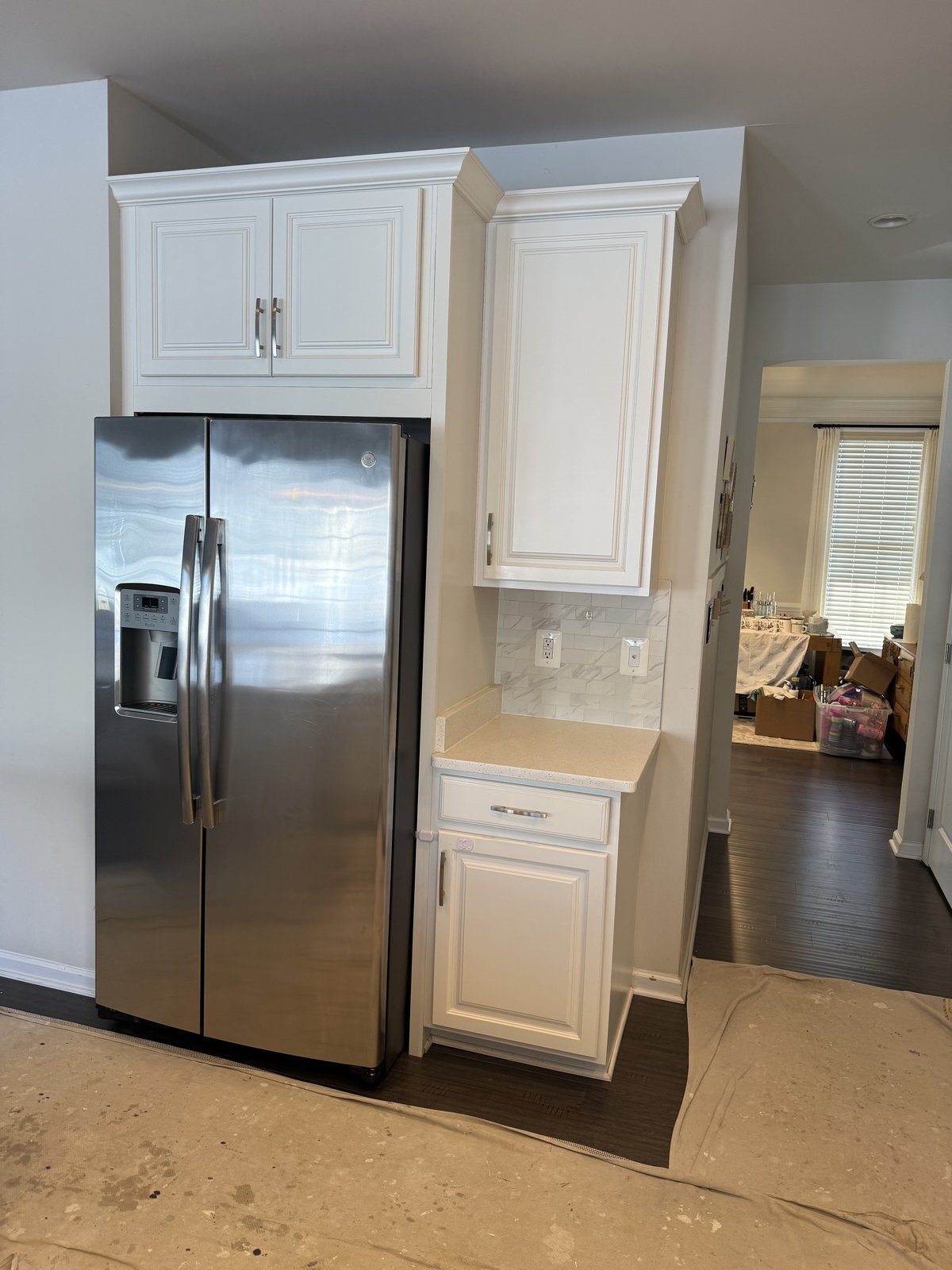 Fridge nook with white cabinets and marble backsplash