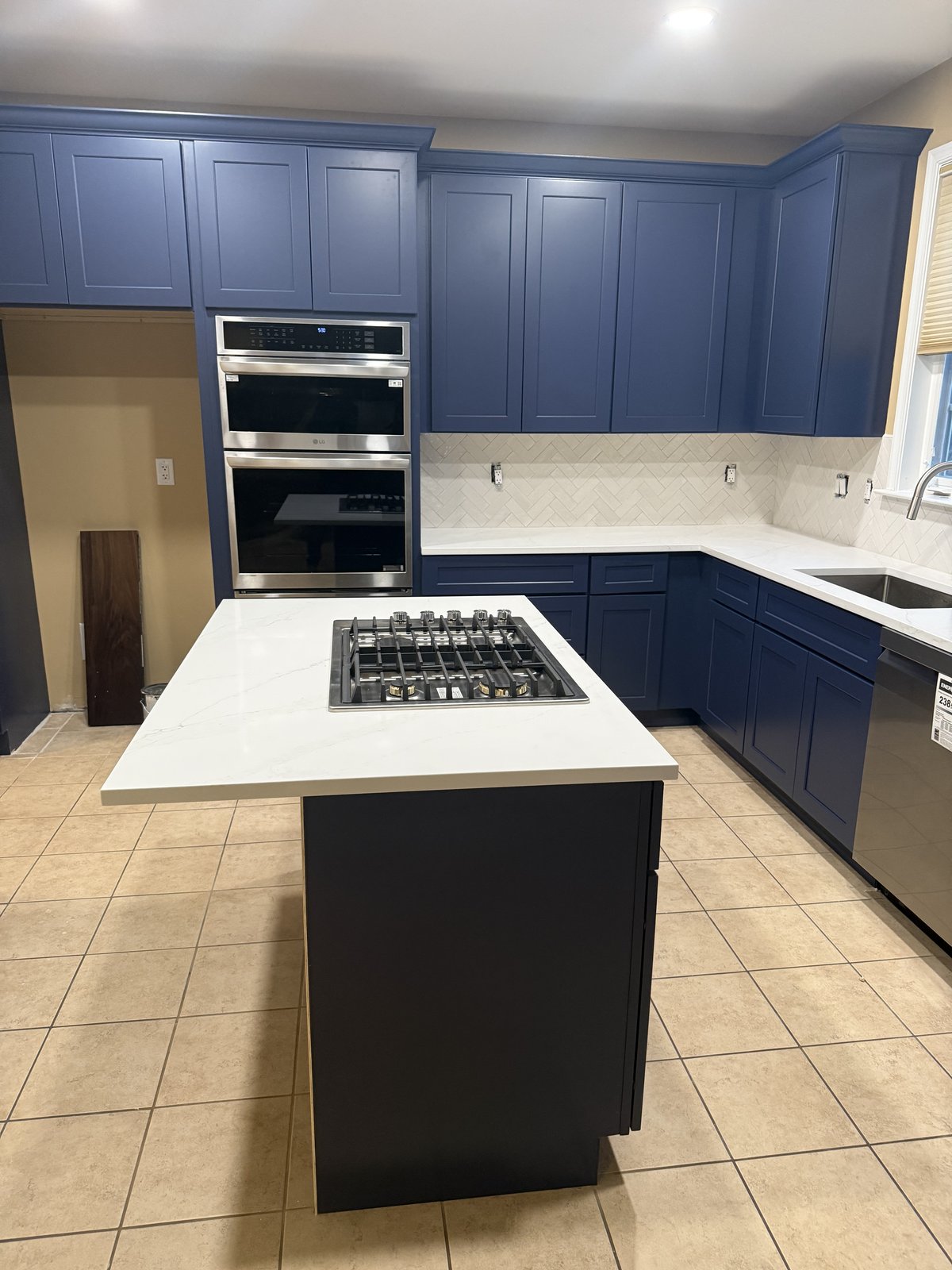 Navy blue kitchen with island cooktop and white quartz
