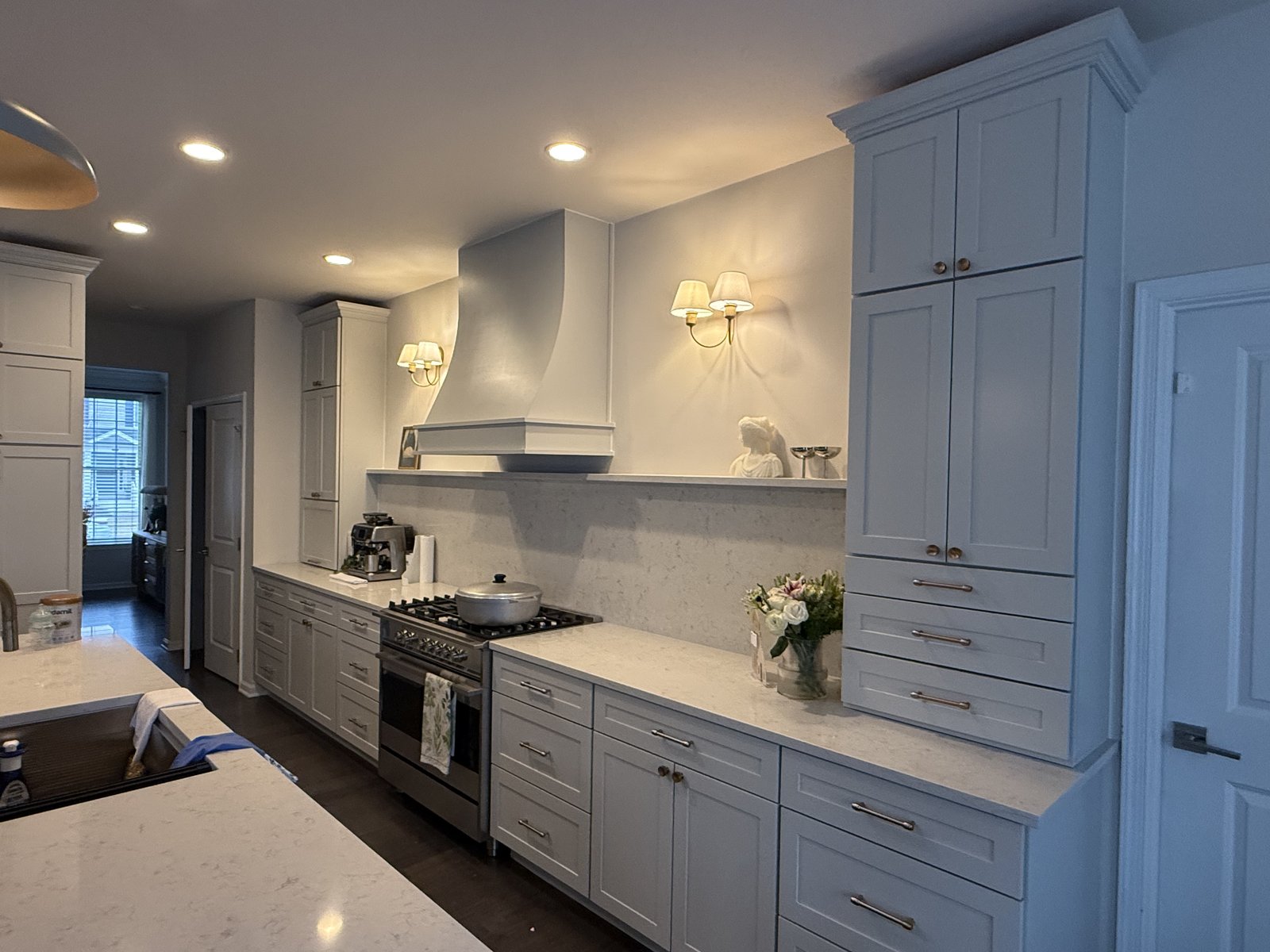 Custom range hood and cabinetry with wall sconces